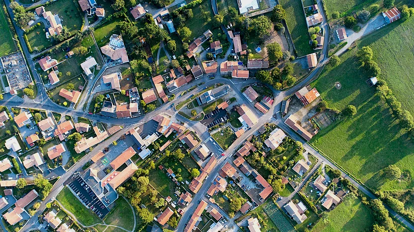 Luftaufnahme eines Dorfes mit vielen kleinen Häusern mit Gärten und Straßen.